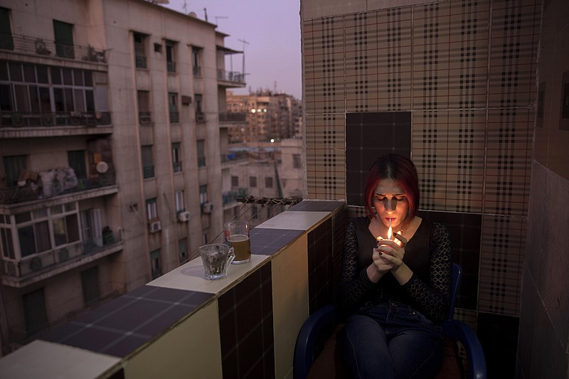 In this Oct. 28, 2019 photo, Egyptian transgender woman and activist Malak el-Kashif smokes a cigarette in the balcony of her apartment in Cairo, Egypt. She has been ostracized by her family and scorned by some who accuse her of tampering with God's creation. She has been attacked by others scandalized by her activism for LGBTQ rights. Legally, she still holds a male's identity card. (AP Photo/Nariman El-Mofty)
