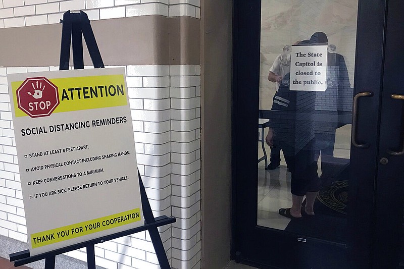 Signs outside the state Capitol in Little Rock, Ark. include reminders about social distancing due to the coronavirus outbreak, Friday, March 27, 2020. The state Senate met at the Capitol to take up a plan to set up a $173 million rainy day fund to address a budget shortfall projected because of the outbreak. (AP Photo/Andrew Demillo)