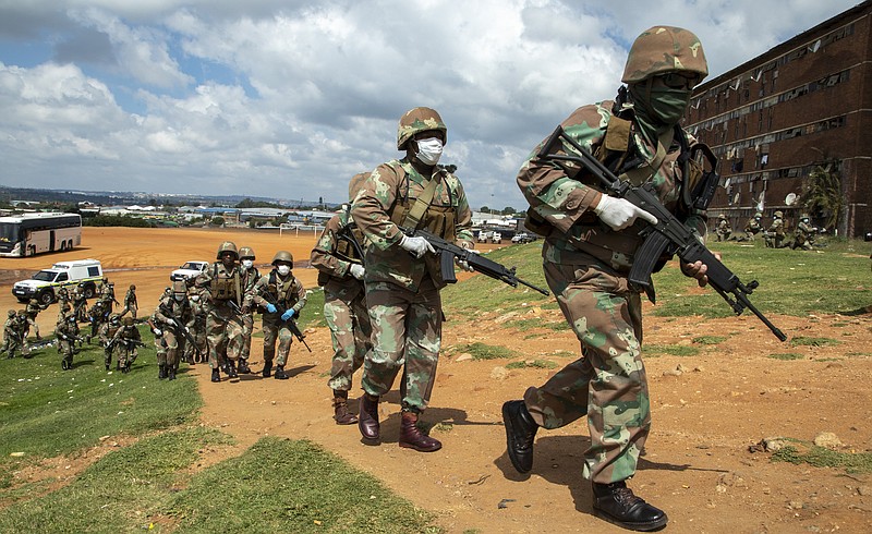 South African National Defence Forces take up positions outside the hostel in a densely populated Alexandra township east of Johannesburg, South Africa, Saturday, March 28, 2020. South Africa went into a nationwide lockdown for 21 days in an effort to control the spread of the COVID-19 coronavirus. The new coronavirus causes mild or moderate symptoms for most people, but for some, especially older adults and people with existing health problems, it can cause more severe illness or death. (AP Photo/Themba Hadebe)