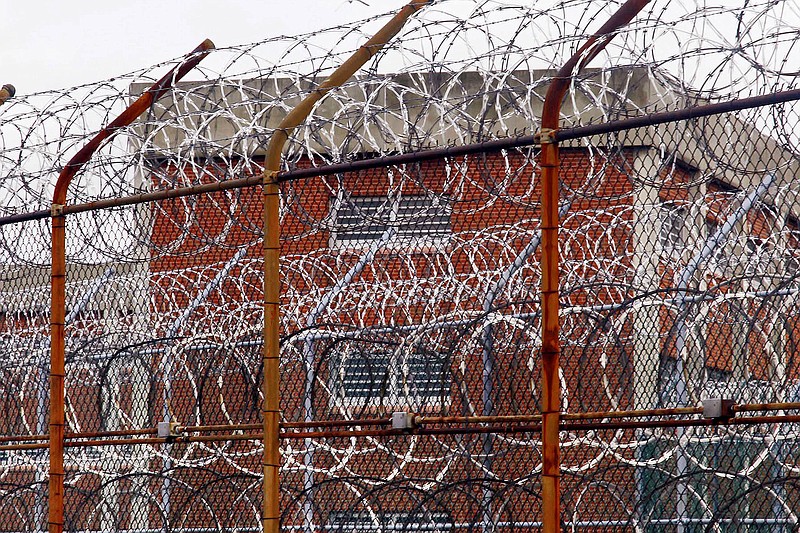 FILE - In this March 16, 2011, file photo, a security fence surrounds inmate housing on the Rikers Island correctional facility in New York. Health experts say prisons and jails are considered a potential epicenter for America’s coronavirus pandemic. (AP Photo/Bebeto Matthews, File)