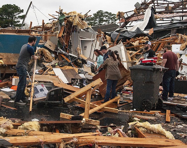 A group of people help clear debris and salvage items from Pawn Depot after a tornado touched down Saturday, March 28, 2020, in Jonesboro, Ark. (Quentin Winstine/The Jonesboro Sun via AP)