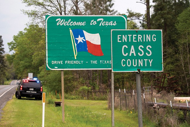 A Department of Public Safety SUV sits along Texas Highway 77 on Monday afternoon in Cass County, Texas. Gov. Greg Abbott announced Sunday that state troopers will patrol highway entry points at the Louisiana border and require "everyone stopped" to also self-isolate, but how aggressively troopers will patrol incoming traffic wasn't immediately clear.