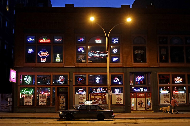 A delivery driver waits outside a bar and grill which only sells take-out and delivery orders as a result of measures to stem the spread of the new coronavirus Friday, March 27, 2020, in Kansas City, Mo. (AP Photo/Charlie Riedel)