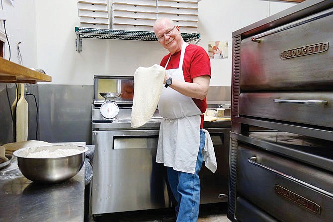 Brian Atkins, co-owner of Brooklyn Pizza, tosses a pizza. His restaurant is one of three currently signed up to provide meals for Our House, Fulton's homeless shelter, with the help of the community.