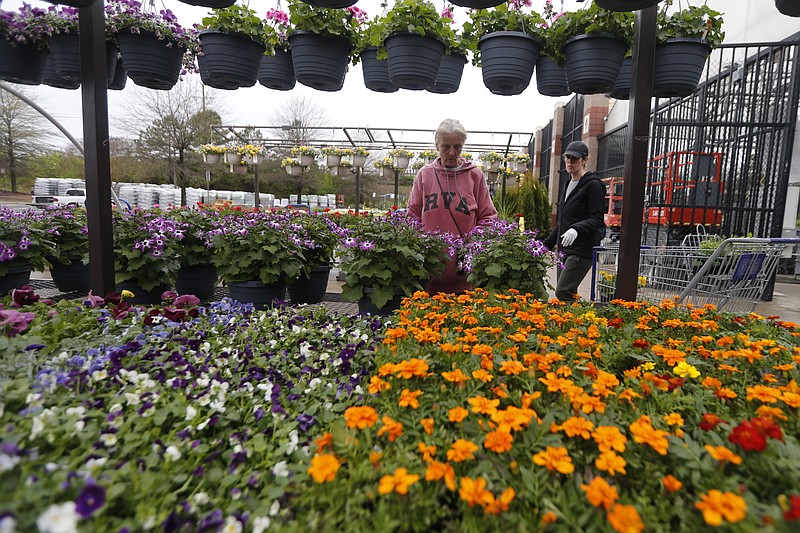 Gail Henrickson, left, and her daughter, Melissa, shop for plants at a local garden center as they stay at home during the coronavirus outbreak Monday March 23 , 2020, in Richmond, Va. The two work at a local restaurant that has closed down and are doing their spring gardening. (AP Photo/Steve Helber)