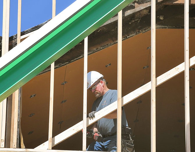 Paul Falter attaches a board for support of the third-floor vertical exterior wall at Communiqué in the 500 block of East Capitol Avenue. The building sustained heavy damage in the May 22, 2019, tornado.