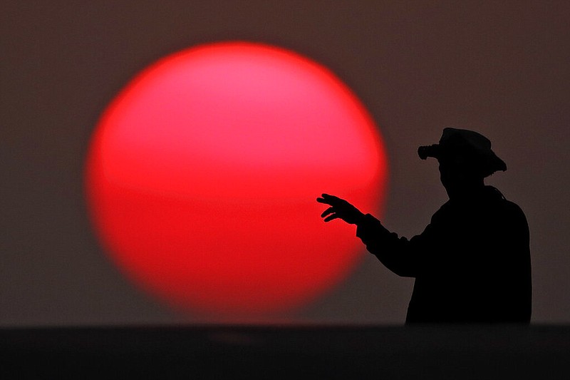 A man crosses an empty downtown street while the sun sets Tuesday, March 31, 2020, in Kansas City, Mo., as a stay-at-home order continues because of the coronavirus outbreak. (AP Photo/Charlie Riedel)