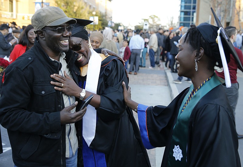 Cheikh Sy hugs his wife Ndeye Ndaw as they share a laugh with their daughter Awa Sy outside College Park Center at the University of Texas at Arlington shortly after graduation ceremonies in Arlington, Texas on Friday, December 13, 2019. Ndeye is earning a master's degree and her daughter Awa earned her bachelor's degree on the same day from UTA. (Vernon Bryant/The Dallas Morning News/TNS)