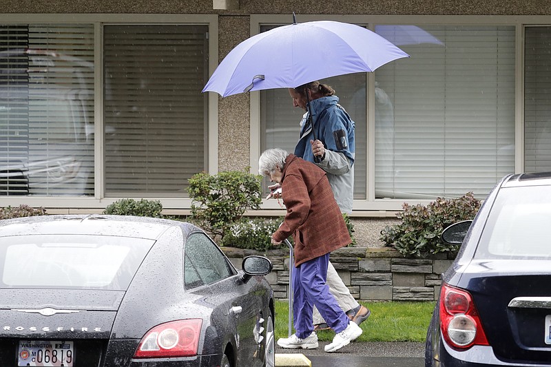 In this March 6, 2020 photo, Charlie Campbell, right, walks with his mother, Dorothy Campbell, to visit his father, Gene, who was staying at the time at the Life Care Center in Kirkland, Wash. Charlie Campbell is nearly 13 years sober, but said he has been feeling tested due to stress from having his father now recovering from the new coronavirus in a hospital, and several other sources of worry and stress in his life. (AP Photo/Ted S. Warren)