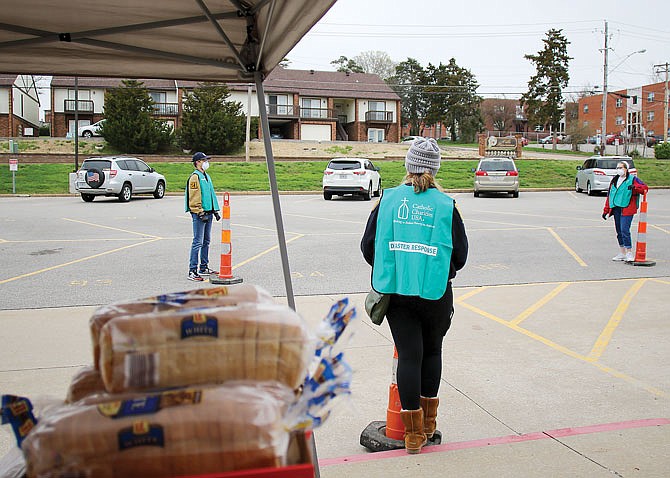 From left, Helias Catholic High School students Will Grothoff, Hannah Bangy and Kennedy Voss practice social distancing Saturday while volunteering at the bread drive at Helias. The bread was loaded onto Catholic Charities trucks and will sit by itself for a period of time before being given out to older people in need. 