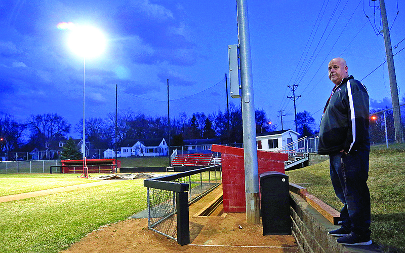 Activities director Dave Boie (right) looks out over the lit baseball field Wednesday night at Richfield High School in Richfield, Minn. Seeking to brighten spirits amid the virus outbreak, the symbolic act of turning on the lights became a movement — fueled by social media with the hashtag #BeTheLight — across the country.