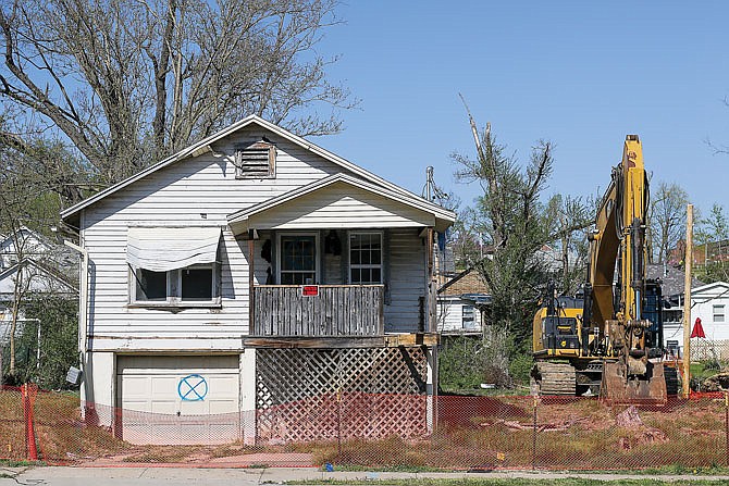 A condemned house sits Friday on Stadium Boulevard, with an excavator next to it. Demolition of the houses along Stadium Boulevard began Friday.