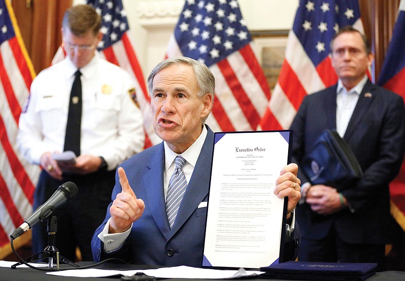 During a press conference at the Texas State Capitol in Austin, Texas Governor Greg Abbott holds a new executive order stating that travel from other states will be limited and subject to 14-day self quarantine, Sunday, March 29, 2020. He also announced the US Army Corps of Engineers and the state are putting up a 250-bed field hospital at the Kay Bailey Hutchison Convention Center in downtown Dallas The space can expand to nearly 1,400 beds. Joining him are Texas Division of Emergency Management Chief Nim Kidd (left) and former State Representative Dr. John Zerwas (right). (Tom Fox/The Dallas Morning News via AP, Pool)