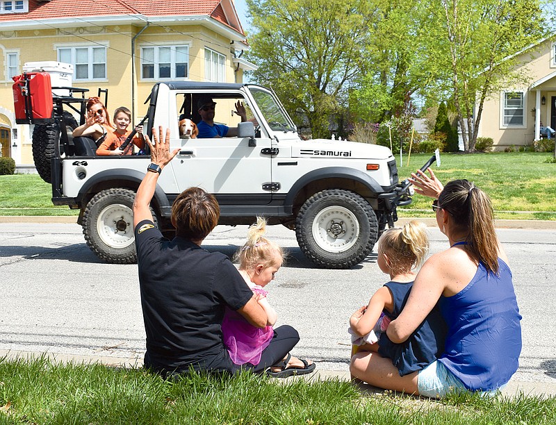 From left, Janice DeLong, Dylan Costello, 2, Emerson Costello, 4, and Morgan Delong Costello wave Sunday as cars drive by along Moreau Drive during the neighborhood's Earth Day Parade. 