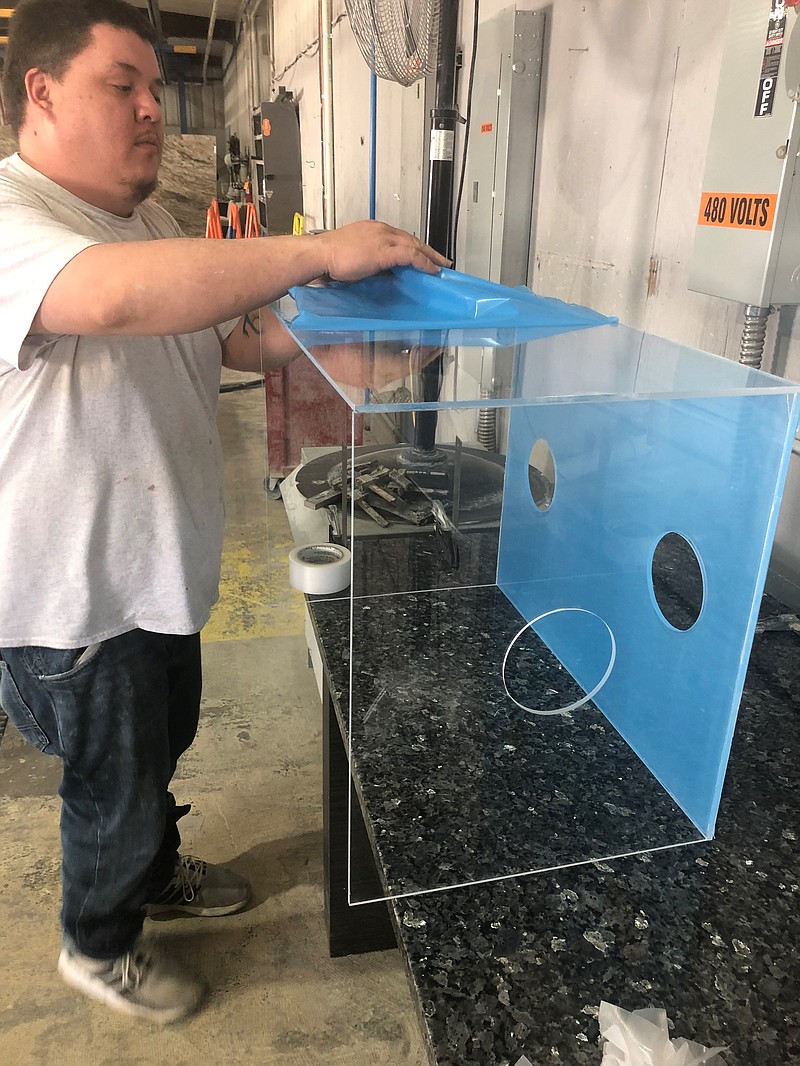 In this undated photo, Stone Studios employee Justin Moore finishes an aerosol protection box to be used by health care providers when intubating COVID-19 patients. The company's main business is selling granite, marble and quartz for uses such as kitchen countertops, but it recently began using its fabrication equipment to build the boxes, which protect clinicians from contamination.