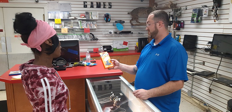 James Coker, manager of More Money Pawn on State Line Avenue, Texarkana, Arkansas, talks merchandise with a customer. According to Coker, pawn shops are a business model that can succeed, whether the economy is up or down.
