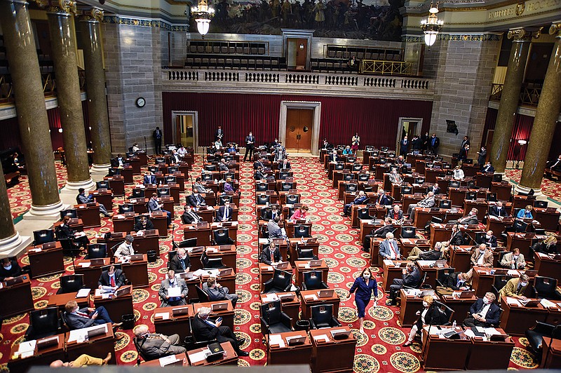 A mask-wearing Rep. Sara Walsh, R-Ashland, walks down the center aisle Monday, April 27, 2020, as she and fellow legislators returned to the Missouri Capitol where the House of Representatives gaveled in around noon. A smattering of representatives were scattered throughout the House floor while several legislators watched debate on their office computer.