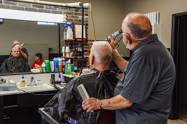 Samuel Frisbie, seated in background, watches with a smile as longtime barber Bob Kasmann makes sure that Dan Smith's flat top haircut is just that, flat. Kasmann, who's been a barber 55 years, works at Southside Barber Shop and knew that reopening after nearly six weeks of a mandatory closure would result in a large crowd anxious for haircuts and shaves. The staff prepared by having disposable capes for customers, wearing masks, having sanitizer on hand to clean after each customer and limiting the number of customers in the shop at one time.