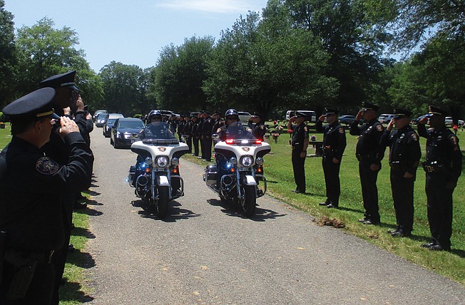  Police officers line a roadway Sunday at Memorial Gardens Cemetery to bid a final salute to Texarkana, Texas, Police Capt. Joe Bunting.