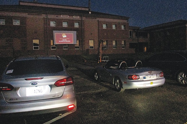 Cars park Saturday in front of an impromptu drive-in theater screen attached to the University of Arkansas Hope-Texarkana campus' Science and Technology building. Campus officials are experimenting with ways to allow people to see movies during the COVID-19 pandemic.
