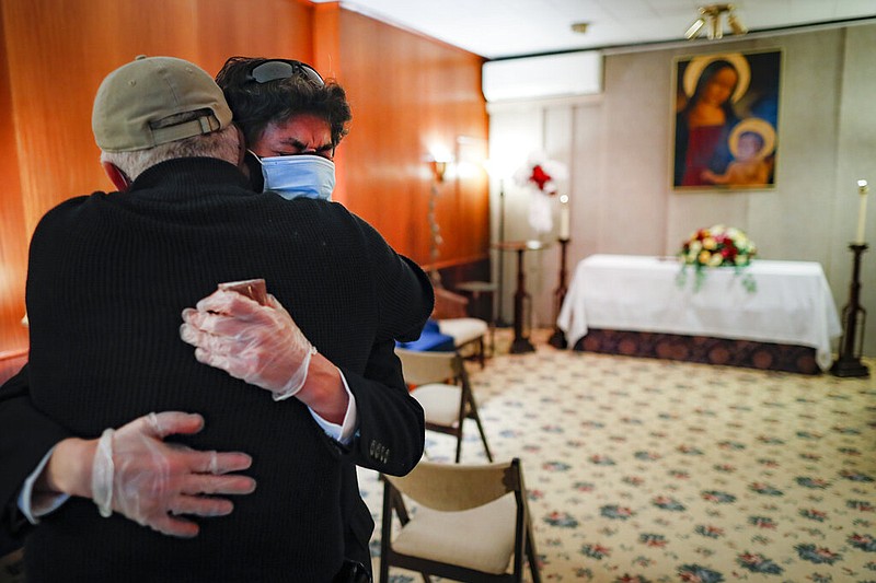 Leonardo Cabaa cries in the arms of his friend Raphael Benevides beside the casket of his father, Héctor Miguel Cabaa, who died of COVID-19 before the funeral home service led by the Rev. Fabian Arias, Monday, May 11, 2020, in the Brooklyn borough of New York. In hard-hit New York City, the coronavirus outbreak has taken a particularly heavy toll on Hispanic communities. (AP Photo/John Minchillo)