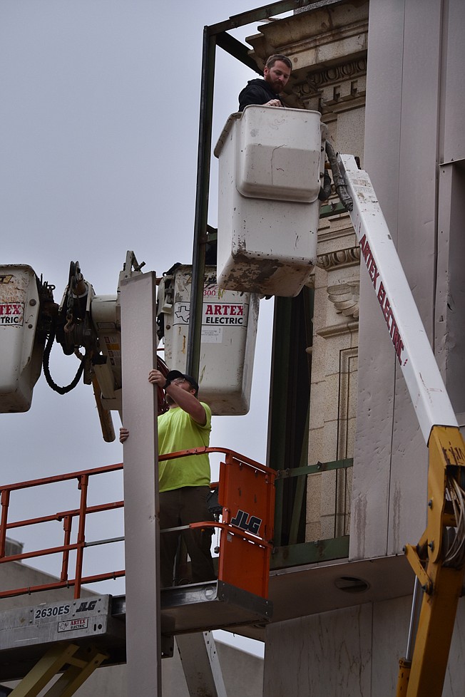 Workers remove aluminum panels from the former Texarkana National Bank building on Tuesday at the corner of West Broad Street and North State Line Avenue. It is the first step in stripping away the veneer that covered the building's original architectural glory. Local developer David Peavy plans to restore the building.