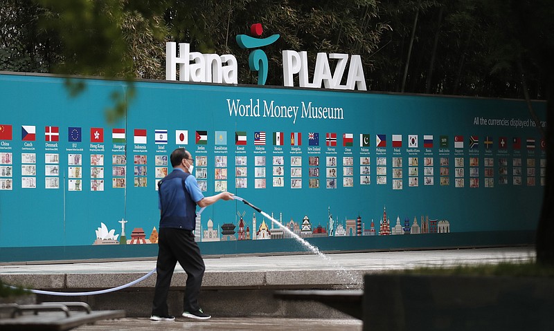 A worker cleans near a bank's currency advertisement board in Seoul, South Korea, Tuesday, May 12, 2020. Shares are lower in Asia as news of fresh outbreaks of coronavirus cases and more infections among White House staff overshadowed hopes Tuesday over reopening economies. (AP Photo/Lee Jin-man)