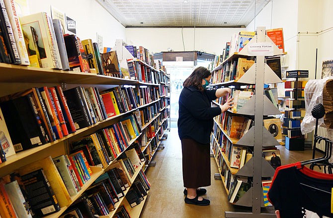 Rebecca Morgan, owner of Well Read Books in downtown Fulton, shelves a tome Wednesday. Fulton's only used bookstore has reopened with precautions in place following the end of Missouri's stay-at-home order.