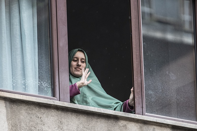 FILE -  In this Monday, May 11, 2020 file photo, Silvia Romano waves from a window of her home, in Milan, Italy. A right-wing lawmaker was reprimanded Wednesday for having called a young Italian woman held hostage in Somalia by Muslim extremists a “neo-terrorist” after she returned home having apparently converted to Islam. Silvia Romano, 24, stepped off an Italian government jet on Sunday wearing the green hijab typical of Somali Muslim women. (AP Photo/Luca Bruno, File )