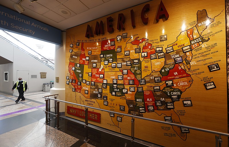 A lone security officer walks past a map of America in the main terminal of Denver International Airport as it gets back to life with the easing of restrictions to check the spread of the new coronavirus Wednesday, May 13, 2020, in Denver. (AP Photo/David Zalubowski)