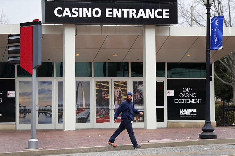 A man crosses the street near an entrance to Lumiere Place Casino, Tuesday, March 17, 2020, in St. Louis. (AP Photo/Jeff Roberson)
