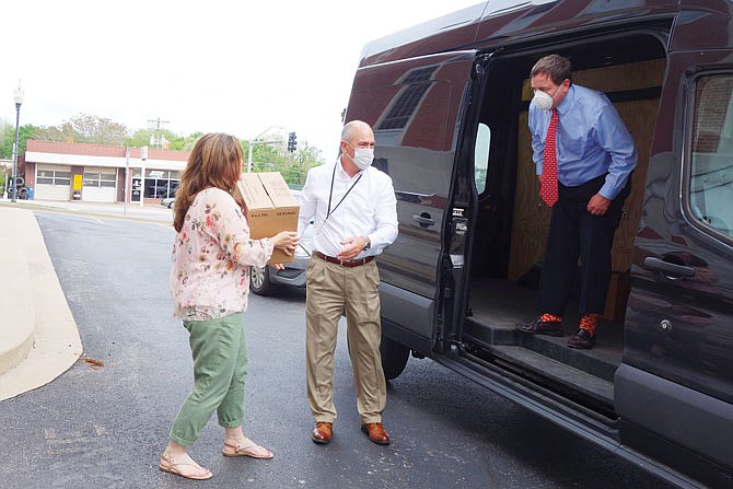 Missouri Secretary of State Jay Ashcroft, right, passes boxes of personal protective equipment to his deputy chief of staff, Harry Roberts, and Callaway County Clerk Ronda Miller. Callaway County was the duo's 13th stop Thursday. When they started, Ashcroft said, the van was filled nearly to capacity with boxed PPE.