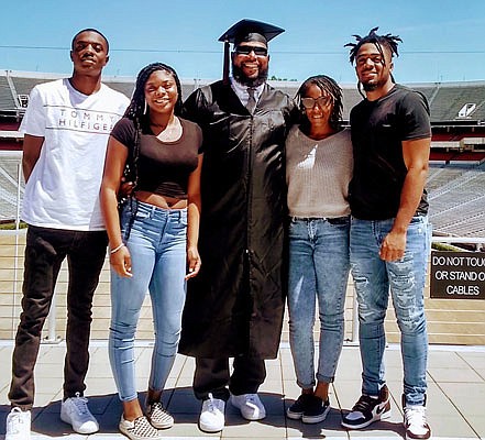 In this May 9 photo provided by Shedrick Wynn, Shedrick Wynn (center) poses in his cap and gown with his family outside Sanford Stadium in Athens Ga.