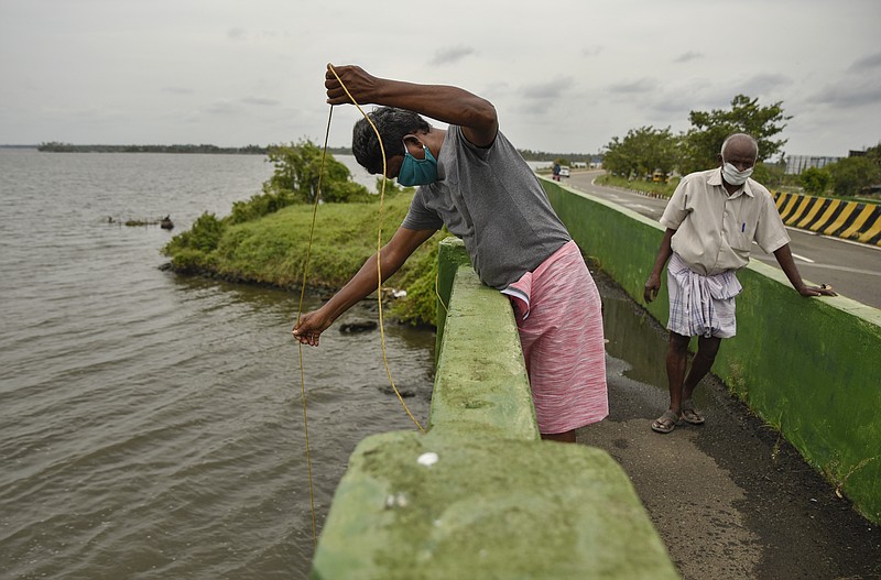 Indians wearing face masks engage in fishing during lockdown to curb the spread of coronavirus in Kochi, Kerala, India, Saturday, May 16, 2020. Prime Minister Narendra Modi's government is due to announce a decision this weekend on whether to extend the 54-day-old lockdown. (AP Photo/R S Iyer)