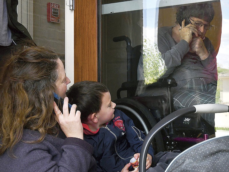 Serena Florio, left, visits her mother, Laurie, for Mother's Day, Sunday, May 10, 2020, at The Villa at Blue Ridge, in Columbia, Mo., amid the coronavirus pandemic. Florio had brought her four children for the visit. (Madi Winfield/Missourian via AP)