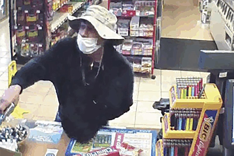 This March 26, 2020 image from surveillance video shows a man, believed to be William Rosario Lopez wearing a surgical mask, with a gun in a Connecticut convenience store.  Just how many criminals are taking advantage of the pandemic to commit crimes is impossible to estimate, but law enforcement officials have no doubt that the numbers are climbing. Reports are starting to pop up across the country, as well as in other parts of the world of crimes that were pulled off in no small part because so many of us are wearing masks. (U.S. District Court of Connecticut via AP)