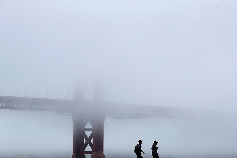 A man wears a face mask while walking on a pier in front of the Golden Gate Bridge during the coronavirus outbreak in San Francisco, Saturday, May 16, 2020. (AP Photo/Jeff Chiu)