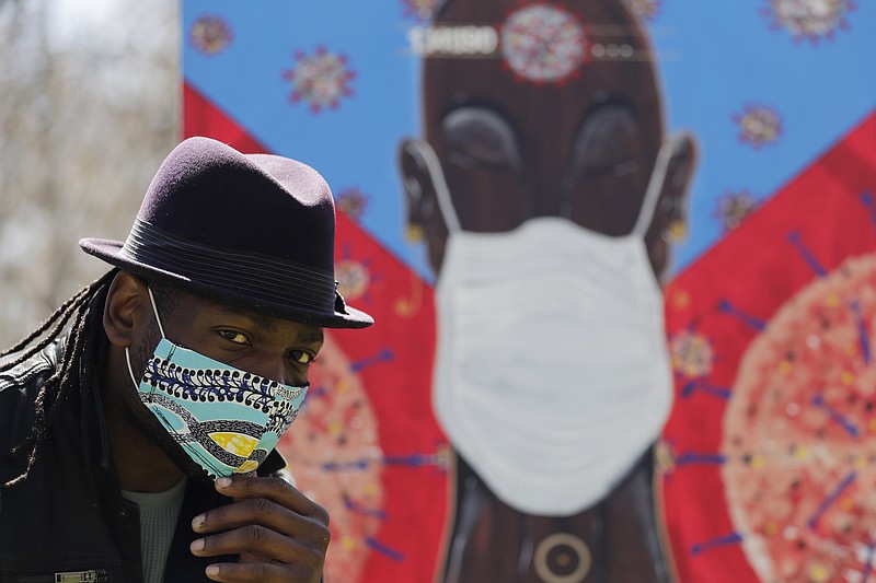 In this Tuesday, April 21, 2020 photo, Obi Uwakwe poses with his painting in Chicago. Uwakwe is an artist/photographer and submitted his art work to the the Illinois State Museum, which is documenting what daily life is like for Illinois families during the coronavirus pandemic. (AP Photo/Nam Y. Huh)