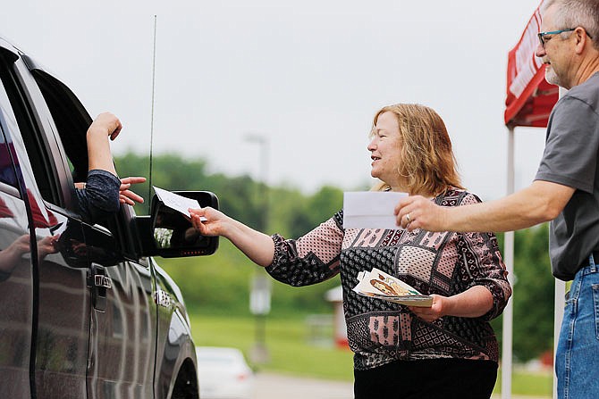 Denise Crider and Mark Buffington accept envelopes from visitors Saturday during a drive-thru send-off for them at Calvary Lutheran High School. Numerous students, parents and faculty dropped off small gifts for Crider and Buffington in addition to their verbal well wishes.