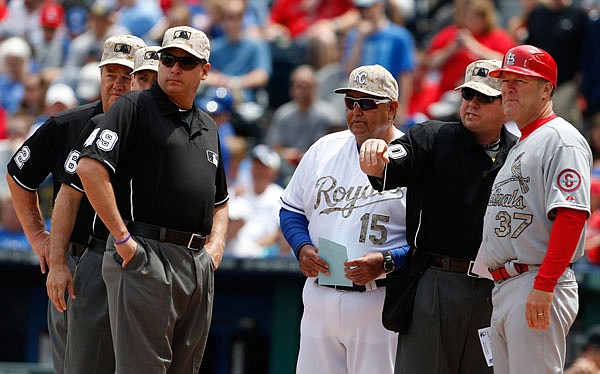 In this May 27, 2013, file photo, Royals bench coach Chino Cadahia and Cardinals first base coach Chris Maloney exchange line-up cards with home plate umpire Rob Drake before a game at Kauffman Stadium.