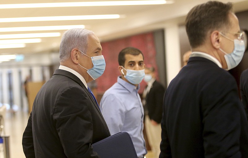 Israeli Prime Minister Benjamin Netanyahu, left, wears a protective face mask, as he makes his way to attend the swearing in ceremony of his new government, at the Knesset, Israel's parliament, in Jerusalem, Sunday, May 17, 2020. Netanyahu is finally swearing in his new government after three deadlocked and divisive elections, a year and a half of political paralysis and another three-day delay because of political infighting in his Likud party over coveted Cabinet posts. (Alex Kolomiensky/Yedioth Ahronoth/Pool via AP)