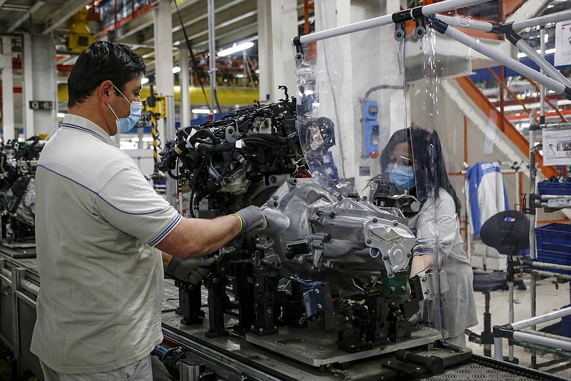 FILE - In this April 27, 2020 file photo, a plastic sheet is laid between two workers needing to face each other to perform their task, as a safety measure for coronavirus contamination, at the Fiat Chrysler Automobiles plants of Atessa, in Central Italy. Fiat Chrysler Automobiles has confirmed a request for an Italian state-backed loan to help the sector relaunch from the coronavirus shutdown, a move that set off debate in Italy over whether such money should be made available to companies with legal headquarters overseas. (Cecilia Fabiano/LaPresse via AP)