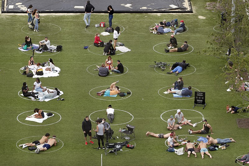 People relax in marked circles for proper social distancing at Domino Park in the Williamsburg neighborhood of Brooklyn during the current coronavirus outbreak, Sunday, May 17, 2020, in New York. (AP Photo/Kathy Willens)