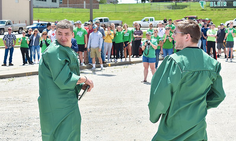 Cole Rackers, left, and J.D. Downing watch as their graduation caps sail through the air during a special Blair Oaks High School graduation ceremony Sunday for the pair, who will serve in the military after high school.