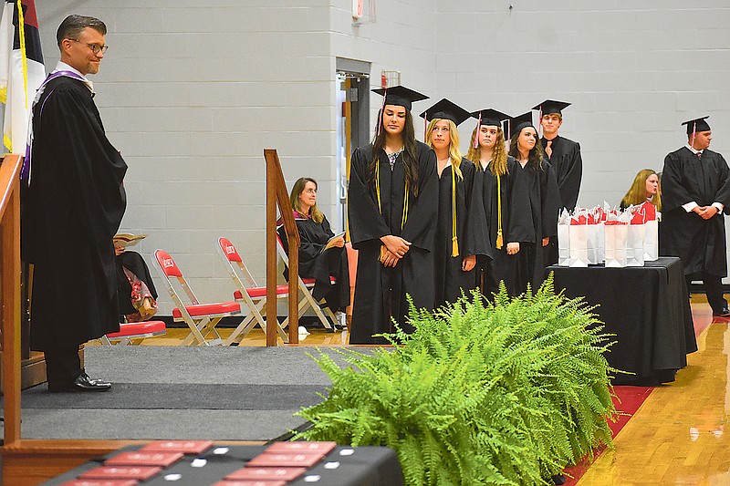 John Christman, executive director of Calvary Lutheran High School, looks on as graduating seniors line up to pick up their diplomas during Sunday's ceremony.