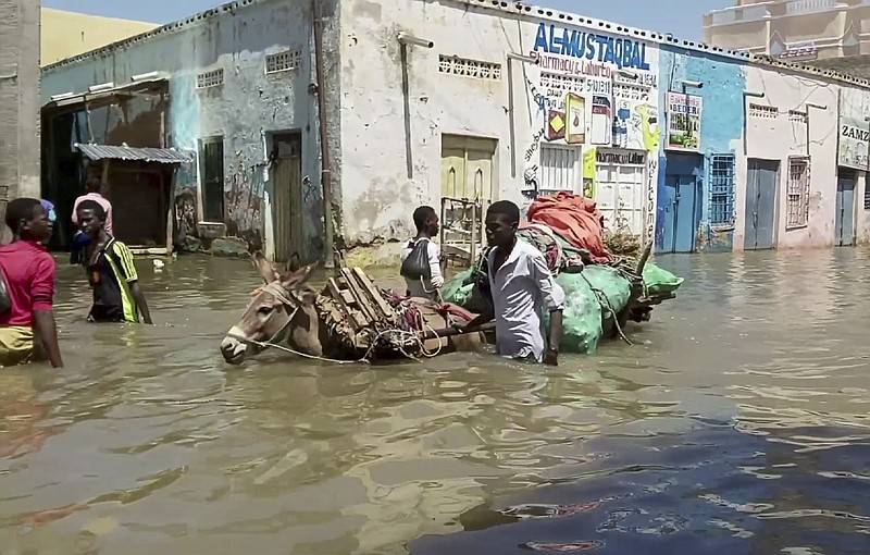 In this image made from video taken Sunday, May 17, 2020, people wade through a flooded street in Beledweyne, central Somalia. Flooding in central Somalia has affected nearly 1 million people, displacing about 400,000, the United Nations said Monday, May 18, 2020 warning of possible disease outbreaks because of crowding where the displaced are seeking temporary shelter. (AP Photo)