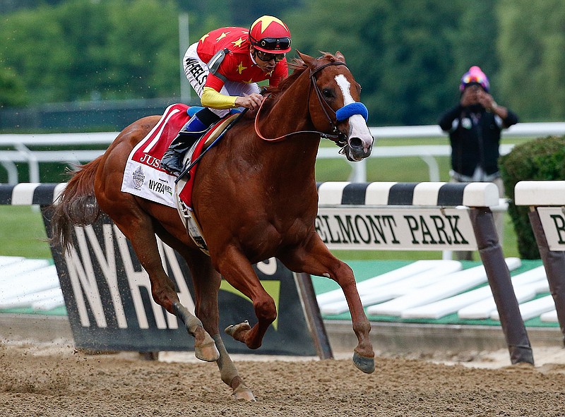 In this June 9, 2018, file photo, Justify,  jockey Mike Smith up, crosses the finish line to win the 150th running of the Belmont Stakes horse race and the Triple Crown at Belmont Park in Elmont, N.Y. The Belmont Stakes will be run June 20, 2020, without fans and serve as the opening leg of horse racing's Triple Crown for the first time in the sport's history. The New York Racing Association on Tuesday, May 19, 2020, unveiled the rescheduled date for the Belmont, which will also be contested at a shorter distance than usual. This is the first time the Belmont will lead off the Triple Crown ahead of the Kentucky Derby and Preakness.(AP Photo/Peter Morgan, File)