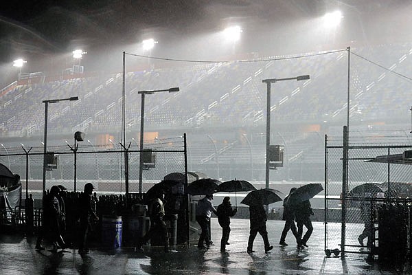 People leave the infield at Darlington Raceway after the NASCAR Xfinity Series race was postponed because of rain Tuesday night in Darlington, S.C.