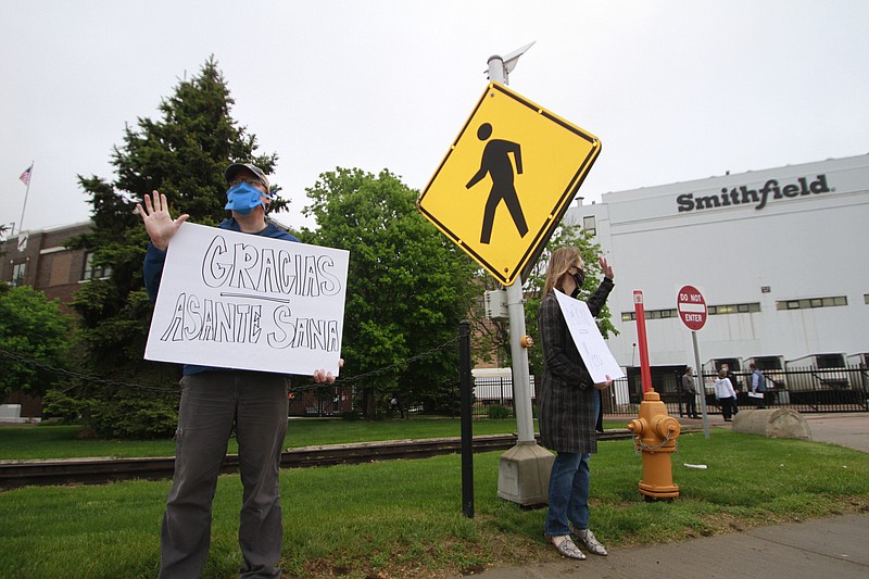 Sioux Falls residents cheered and held thank you signs to greet employees of a Smithfield pork processing plant as they begin their shift on Wednesday May 20, 2020, in Sioux Falls, S.D. Smithfield called many employees back to work after it closed the plant for more than three weeks because of a coronavirus outbreak that infected over 800 employees. (AP Photo/Stephen Groves)