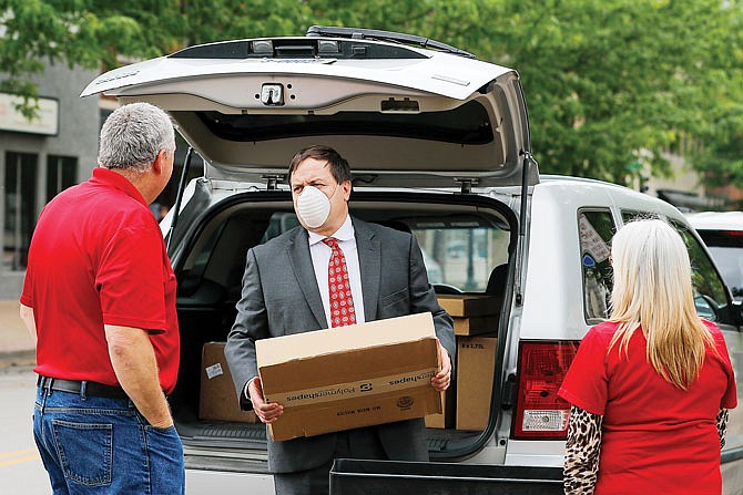 Missouri Secretary of State Jay Ashcroft, center, loads a box of face shield kits onto a cart Thursday, May 28, 2020, while talking to Cole County Clerk Steve Korsmeyer, right, outside the Cole County Courthouse Annex on High Street. 